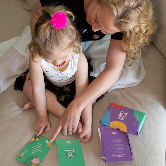 A woman and child playing with cards on the couch